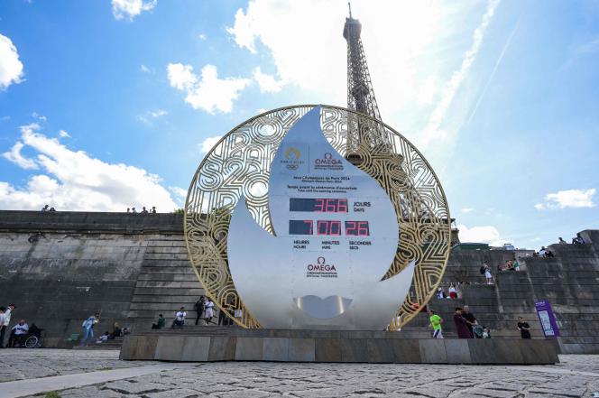 Pedestrians walk past a board displaying the countdown to the start of the Paris 2024 Olympic Games in front of the Eiffel Tower in Paris, on July 26, 2023. On July 26, 2023, the Paris 2024 Olympic games officially enter the last year before the opening ceremony on the Seine river. (Photo by Alain JOCARD / AFP)