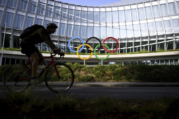 A cyclist rides past the Olympic House, headquarters of the International Olympic Committee (IOC) at the opening of the executive board meeting of the International Olympic Committee (IOC), at the Oly ...